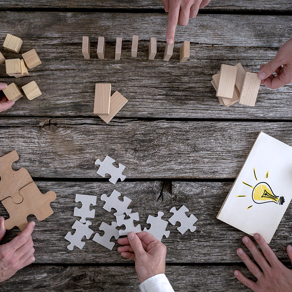 Des collègues manipulant des blocs de bois et des pièces de puzzle pour planifier une stratégie dans l'entreprise